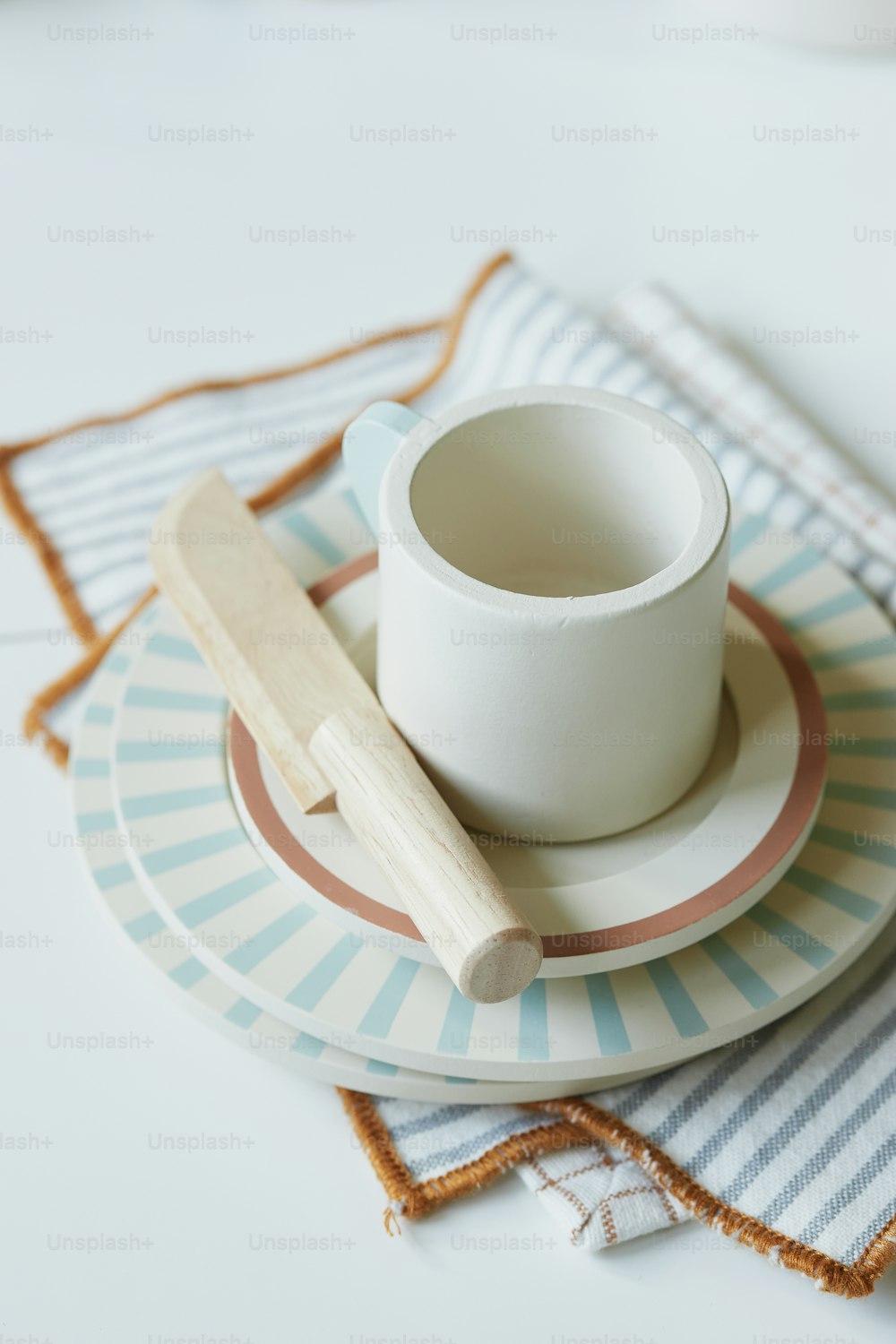 a cup on a plate with a wooden spoon