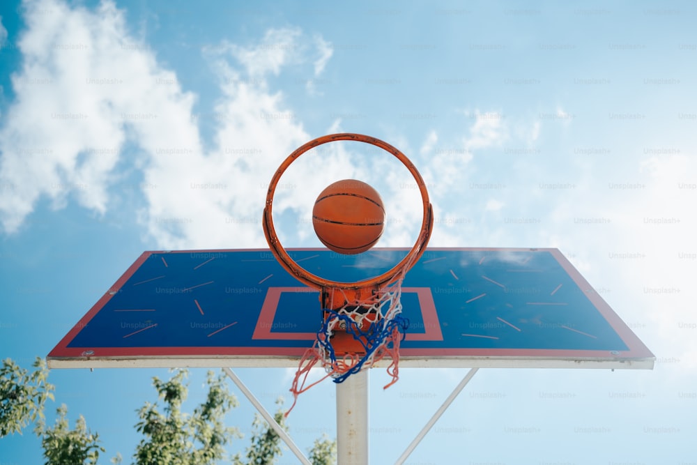 Un pallone da basket che attraversa il canestro in una giornata di sole