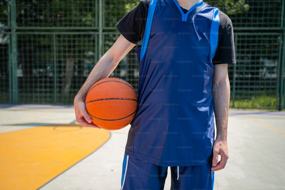 Un uomo che tiene un pallone da basket su un campo da basket
