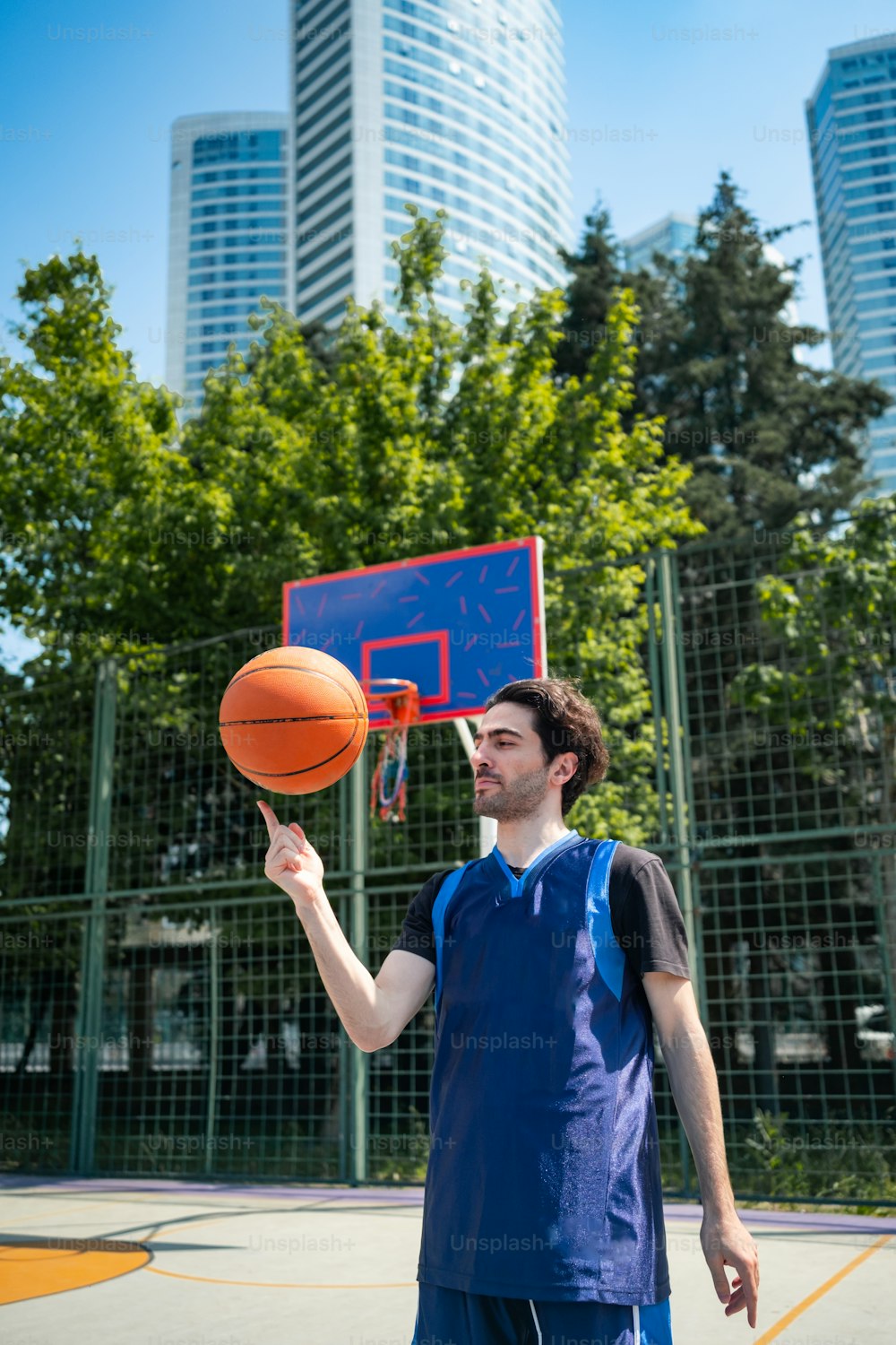 Un uomo che tiene un pallone da basket nella mano destra mentre è in piedi su un campo da basket