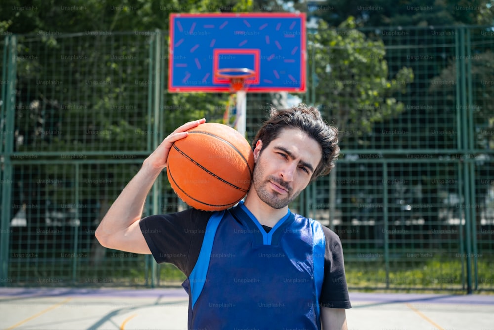 Un uomo che tiene un pallone da basket davanti a un canestro da basket