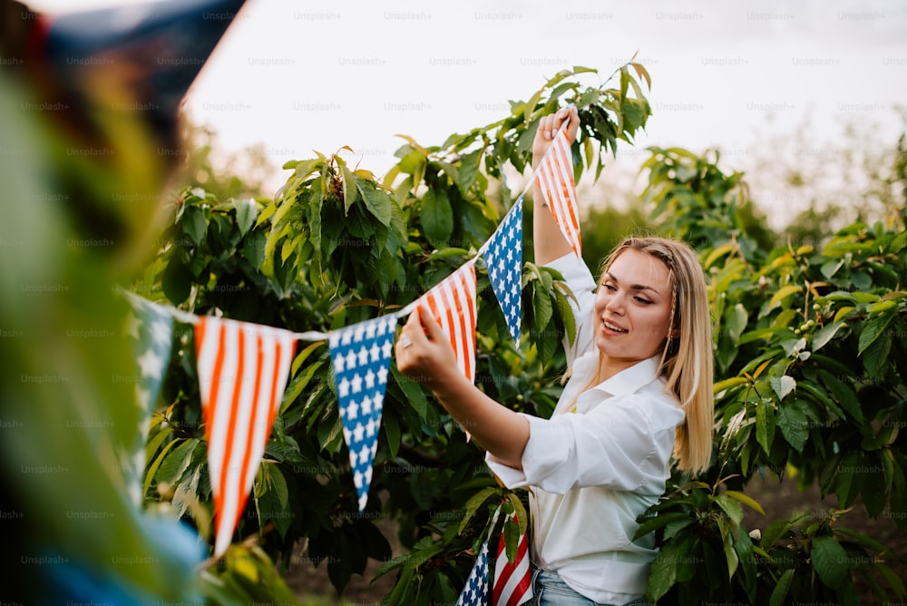 a woman holding american flags in a field