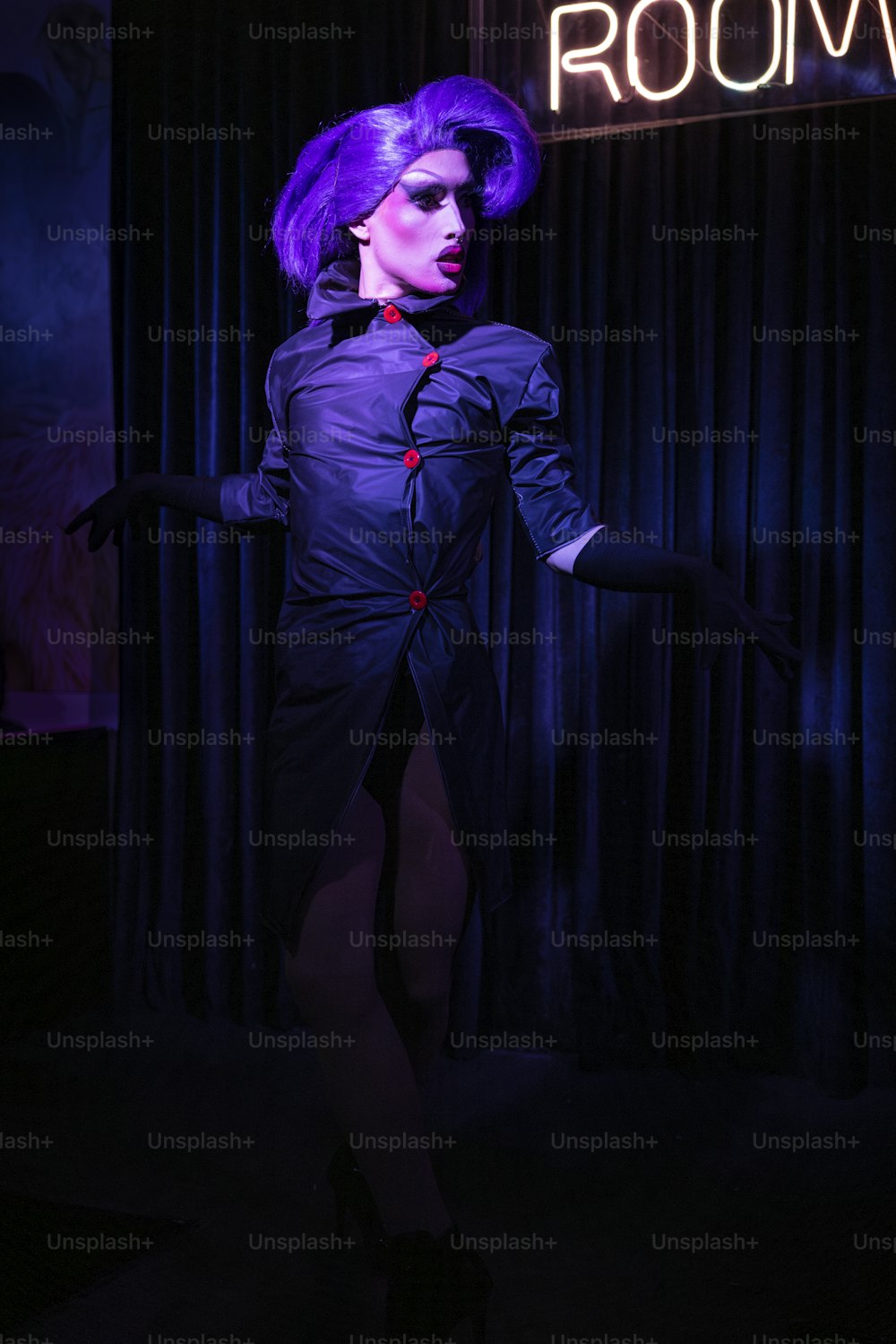 Una donna con i capelli viola è in piedi in una stanza buia