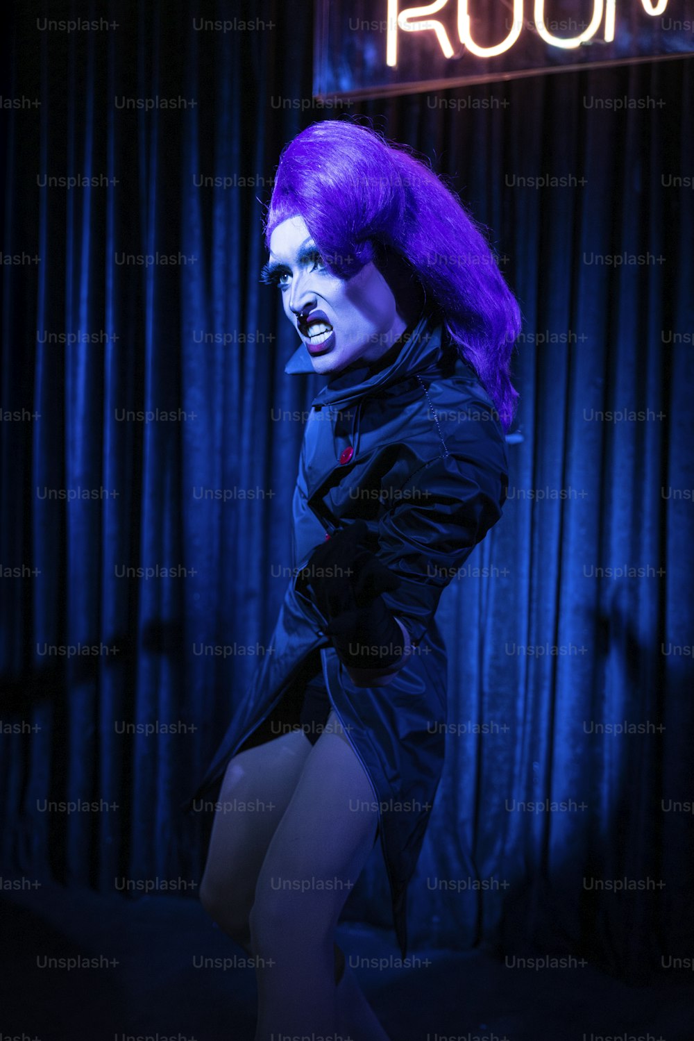 ネオンサインの前に立つ紫色の髪の女性