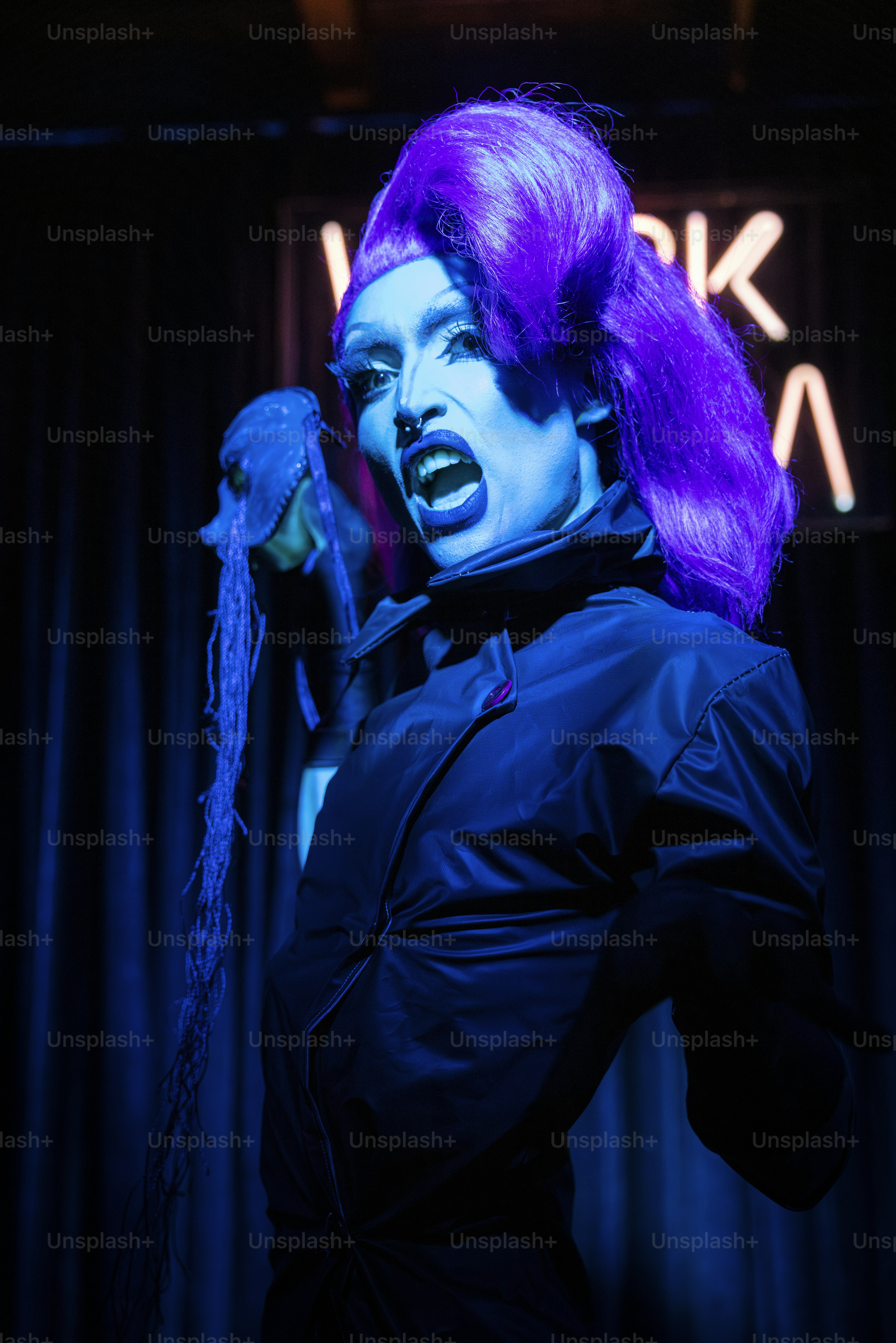 Una mujer con cabello morado y maquillaje sosteniendo un teléfono celular