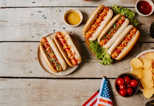 a table topped with plates of hot dogs and chips