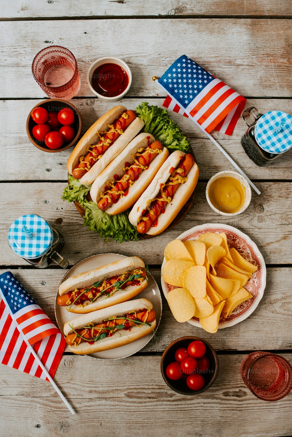 a table topped with plates of hot dogs and chips