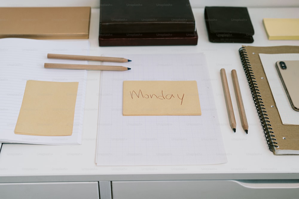 uma mesa com bloco de notas, caneta, caderno e lápis