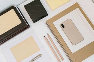 una scrivania con un quaderno, un blocco note, una penna e un telefono cellulare