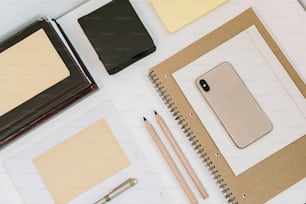 a desk with a notebook, notepad, pen, and a cell phone