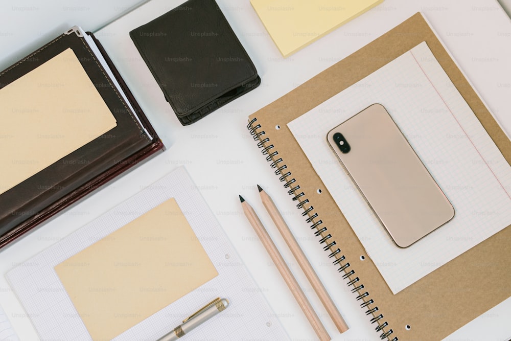 uma mesa com caderno, bloco de notas, caneta e celular