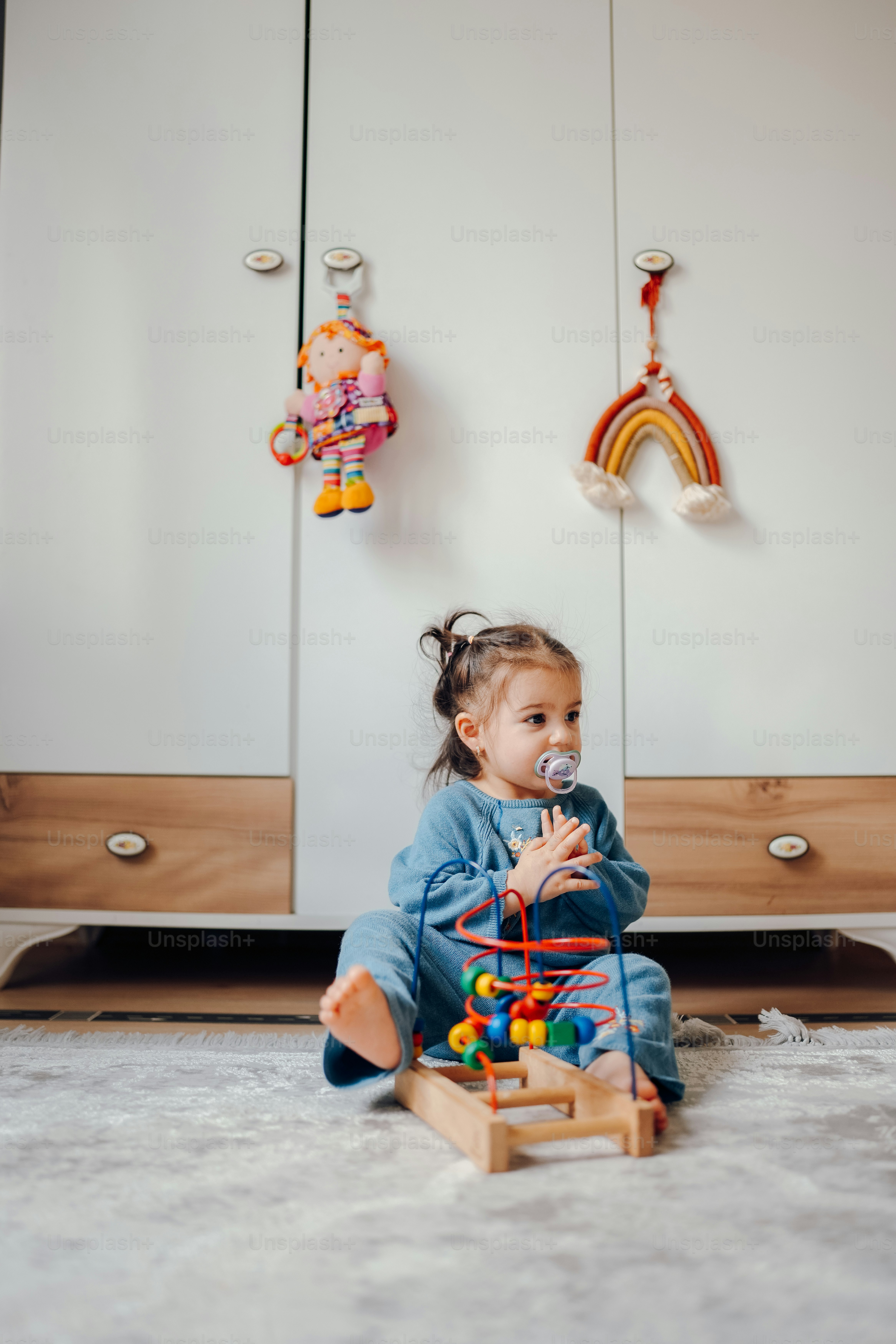 a little girl sitting on the floor playing with a toy