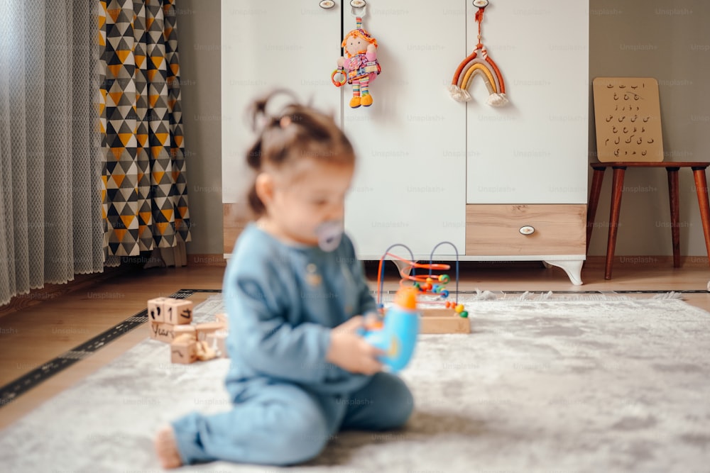 une petite fille assise par terre jouant avec un jouet