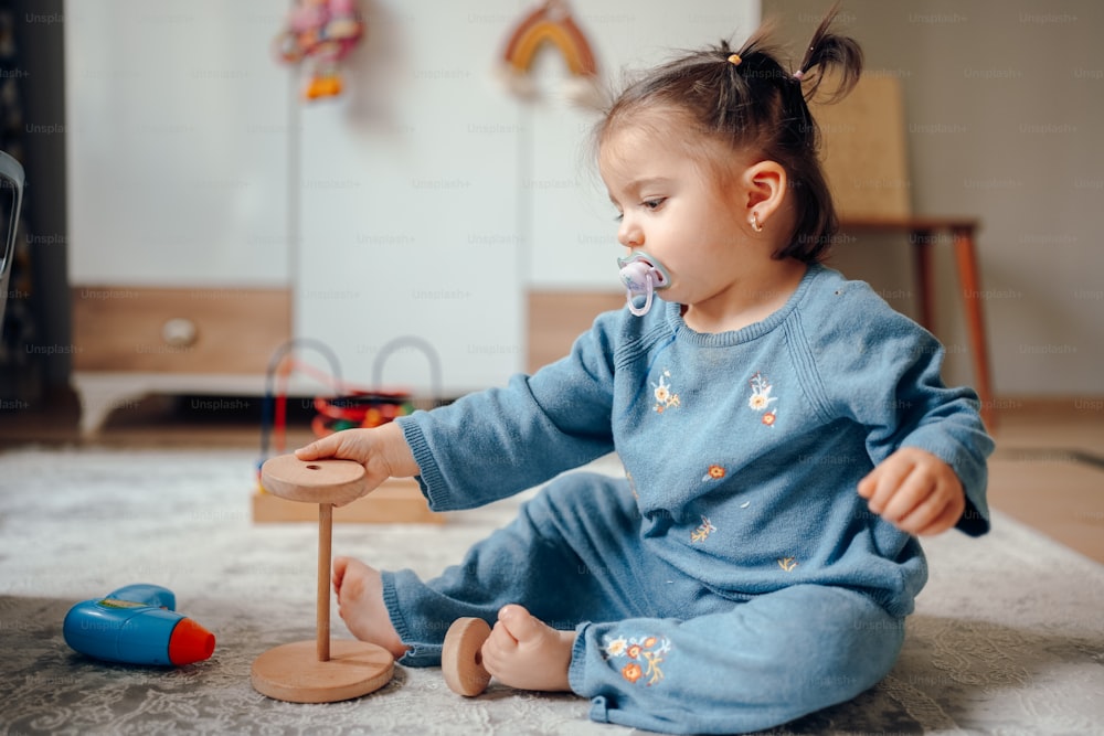 une petite fille assise par terre jouant avec un jouet