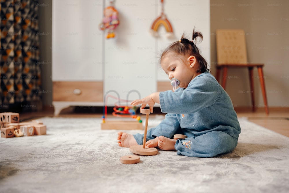 Un bebé jugando con un juguete de madera en el suelo