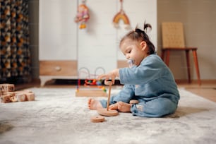 Un bebé jugando con un juguete de madera en el suelo