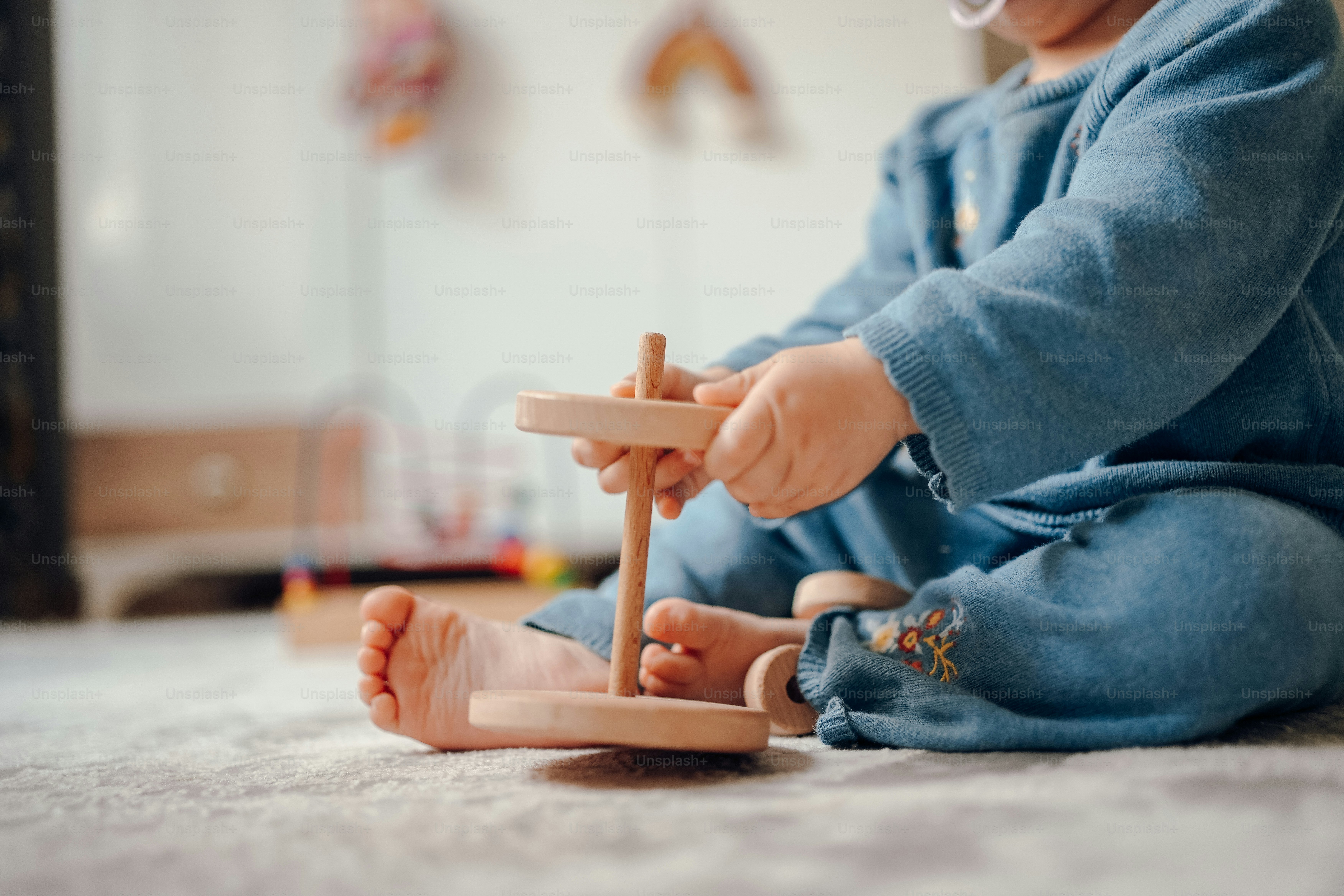 a baby playing with a wooden toy on the floor