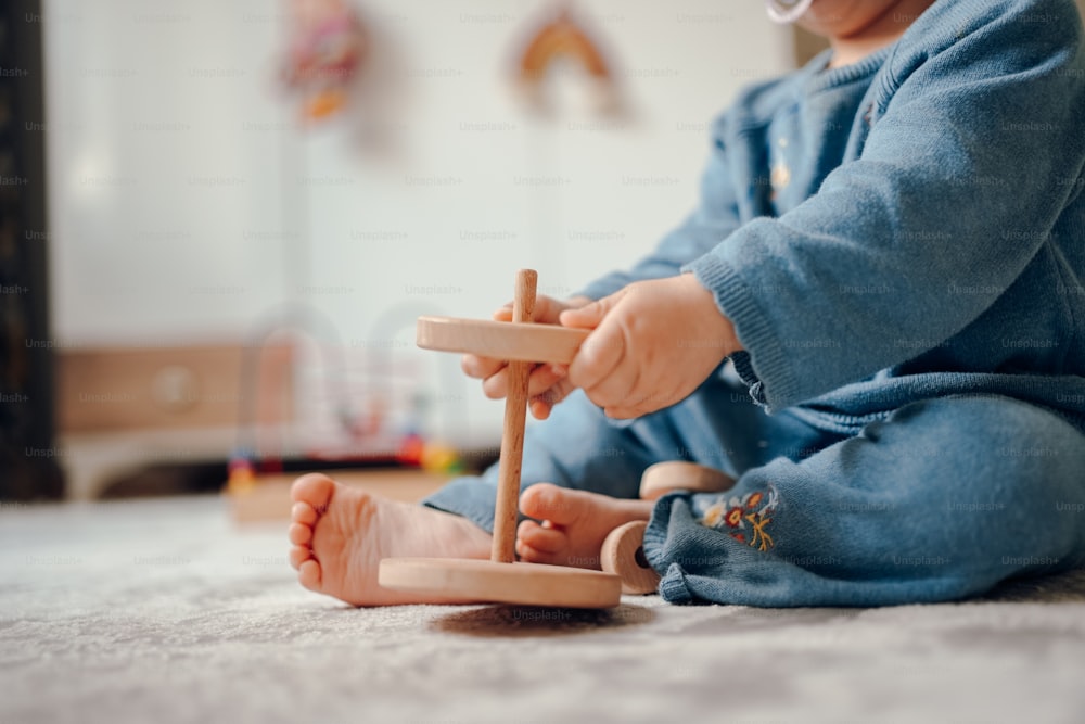 un bébé jouant avec un jouet en bois sur le sol