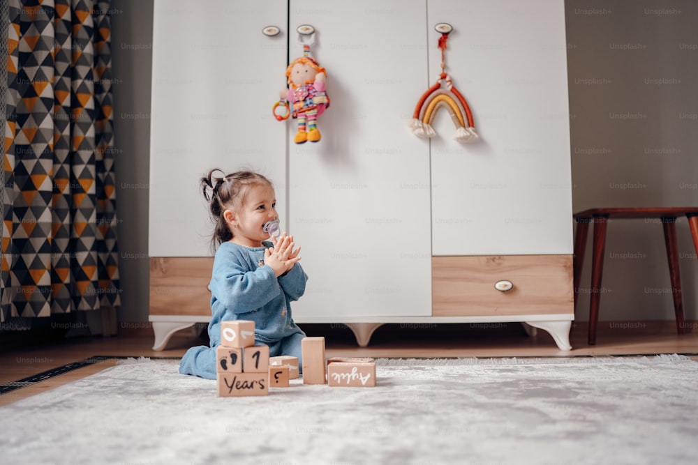 a little girl sitting on the floor playing with blocks