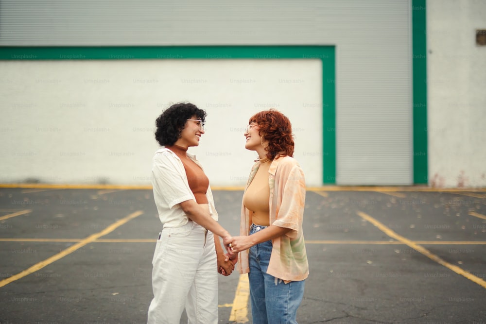 um casal de mulheres em pé um ao lado do outro em um estacionamento