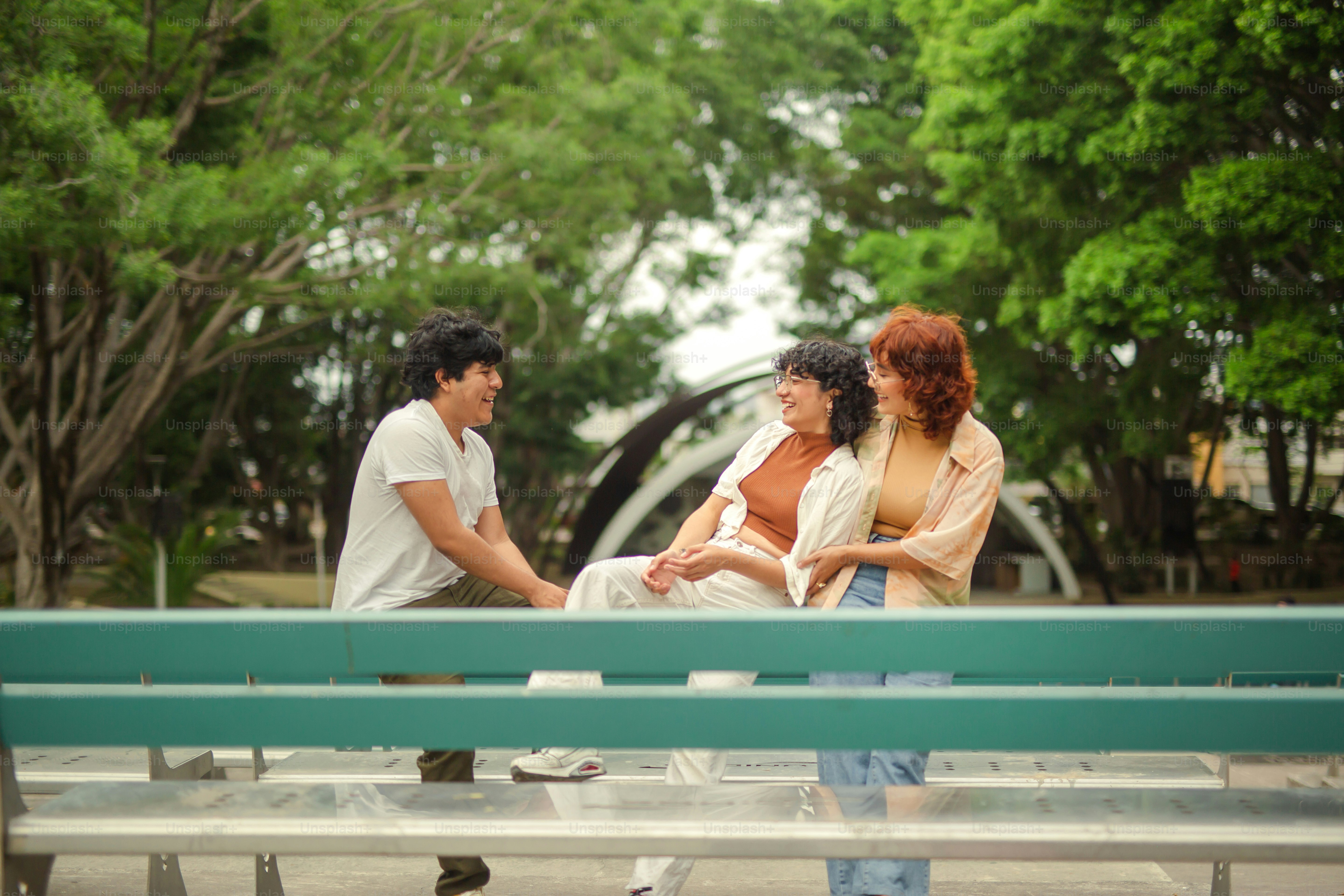 three people sitting on a bench in a park