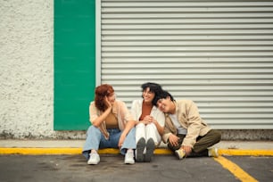 three people sitting on the ground in front of a building