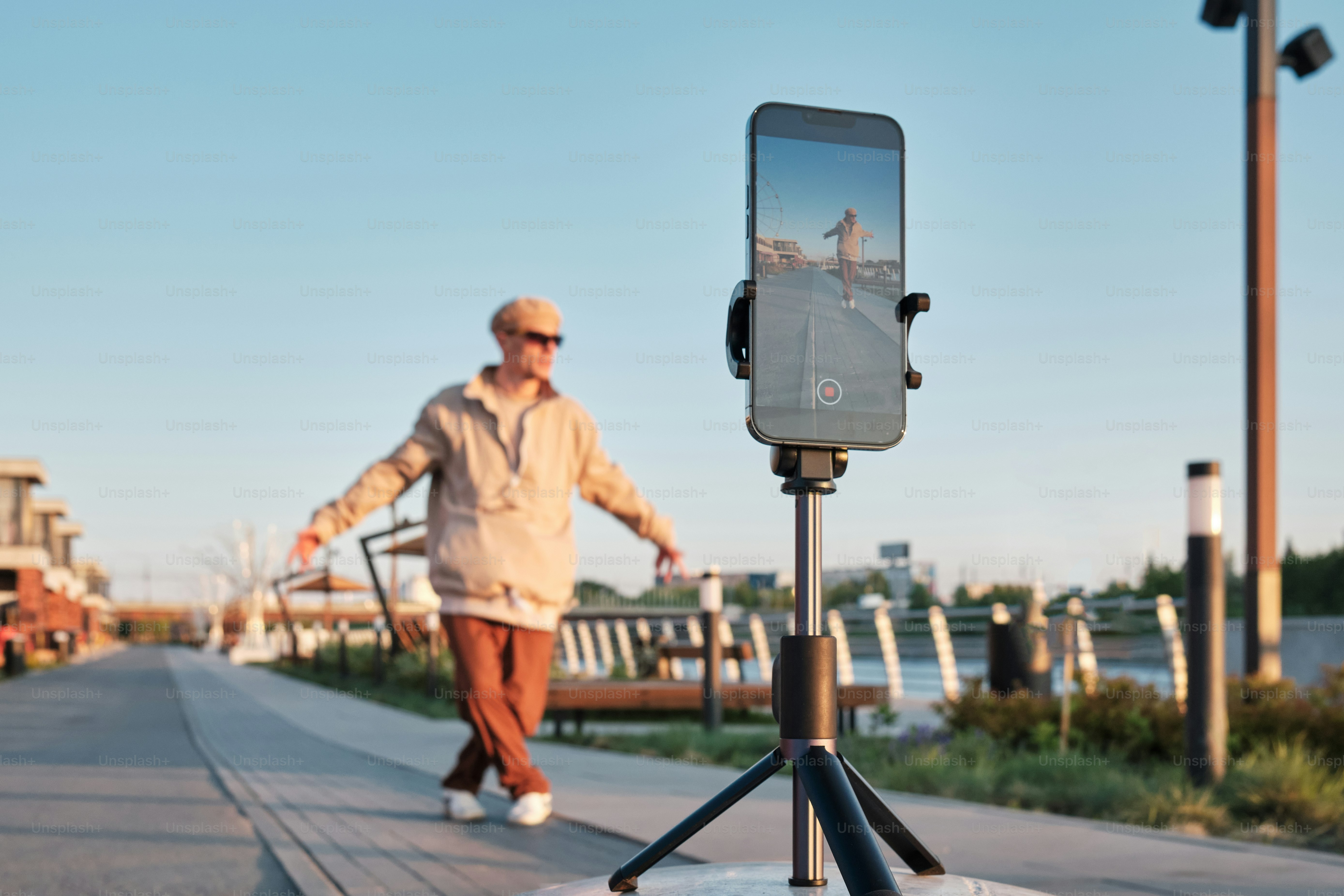 a man walking down a sidewalk with a cell phone on a tripod