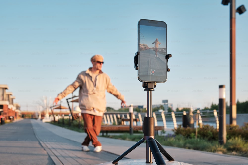 a man walking down a sidewalk with a cell phone on a tripod