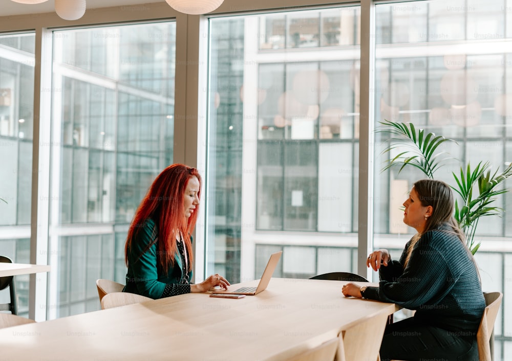 two women sitting at a table with a laptop