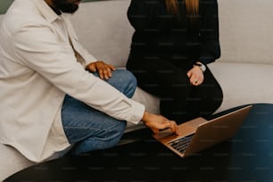 a man and a woman sitting on a couch looking at a laptop