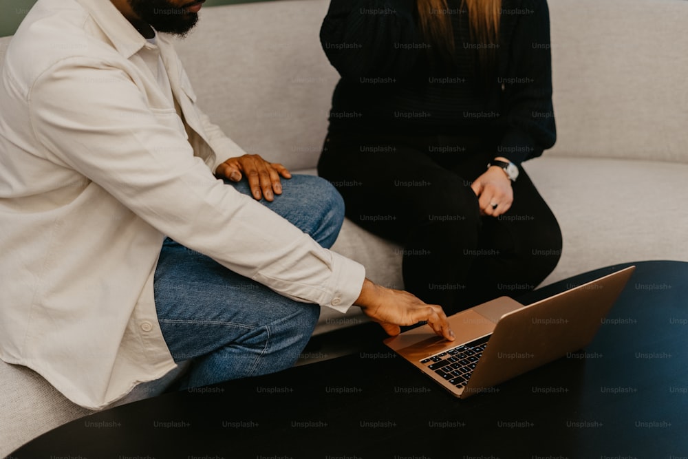 Ein Mann und eine Frau sitzen auf einer Couch und schauen auf einen Laptop