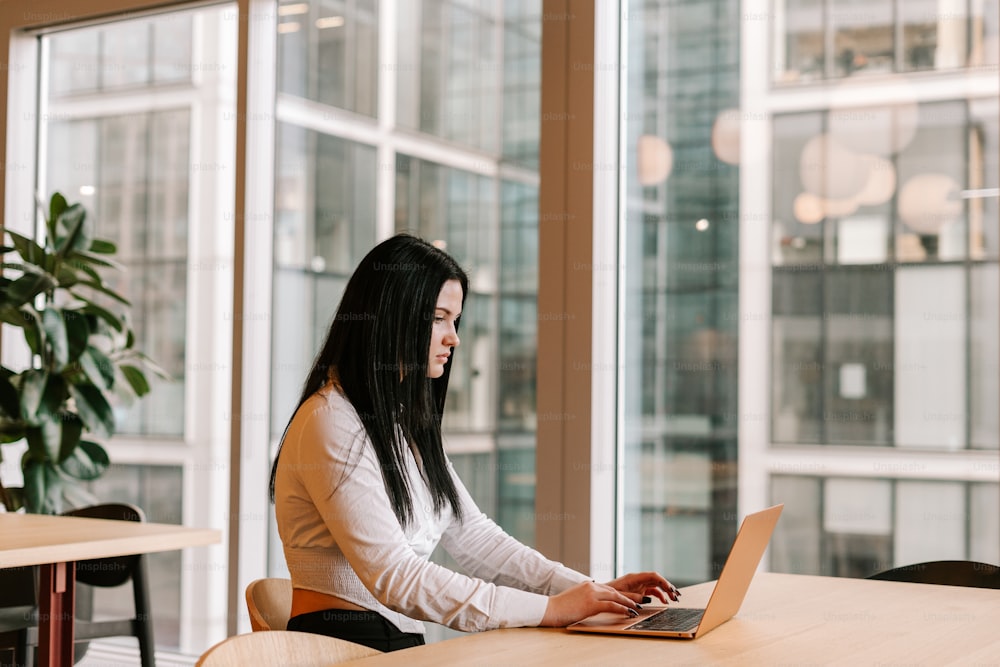 a woman sitting at a table using a laptop computer