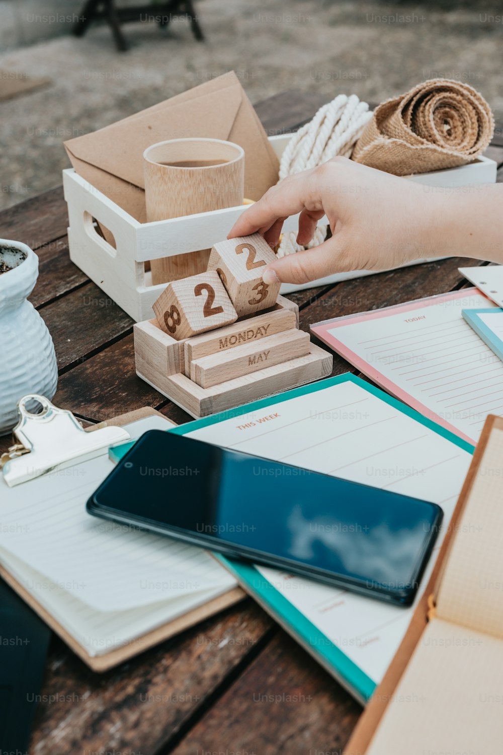 a wooden table topped with notebooks and a phone