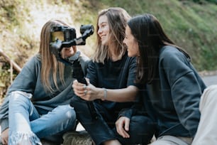 three women sitting on the ground with a camera