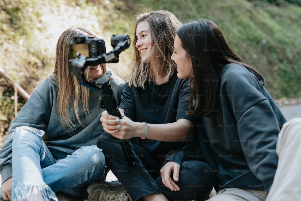 three women sitting on the ground with a camera