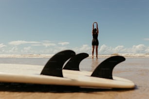 a woman standing on a beach next to surfboards