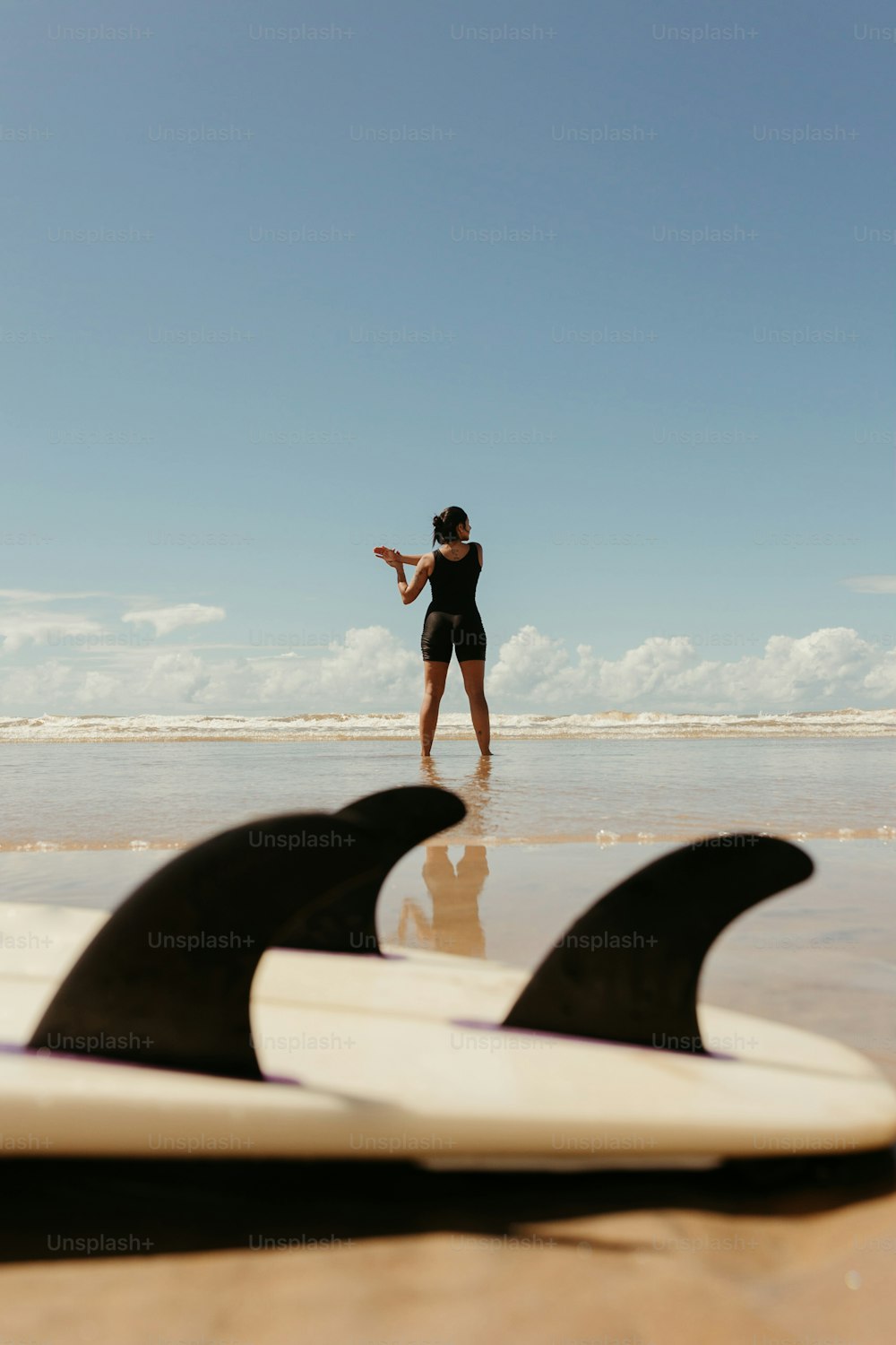 a woman standing on a beach next to two surfboards