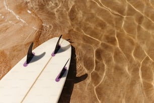 a white surfboard laying on top of a sandy beach