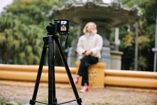 Una donna seduta su una panchina accanto a una telecamera