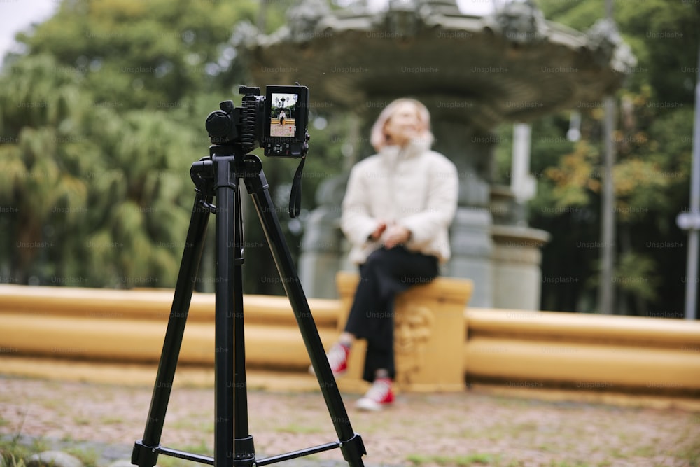 a woman sitting on a bench next to a camera