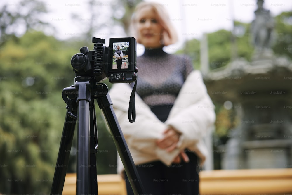 Una mujer de pie junto a una cámara en un trípode
