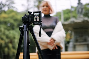 Una donna in piedi accanto a una macchina fotografica su un treppiede