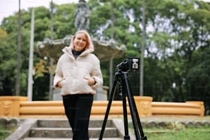 Una mujer está parada frente a una cámara en un trípode