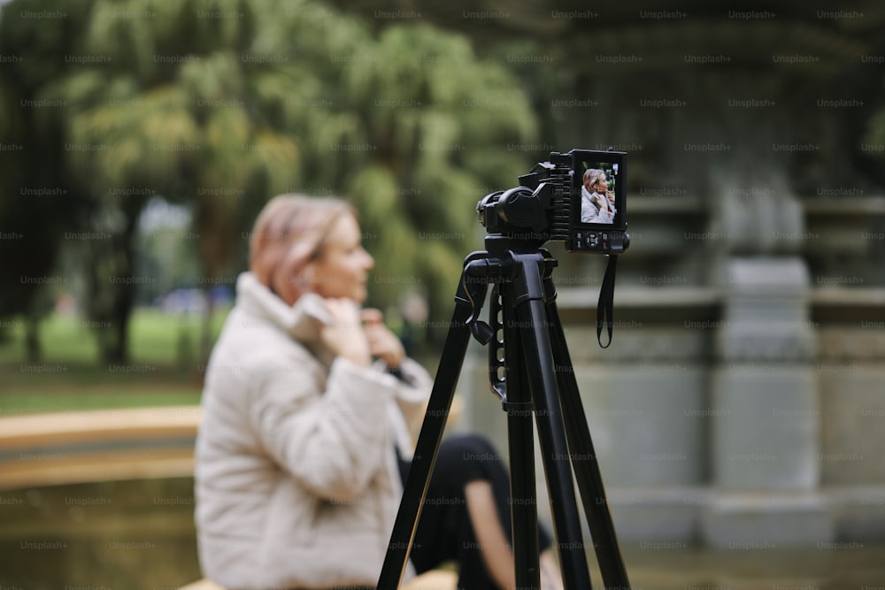 una donna seduta su una panchina con una macchina fotografica su un treppiede