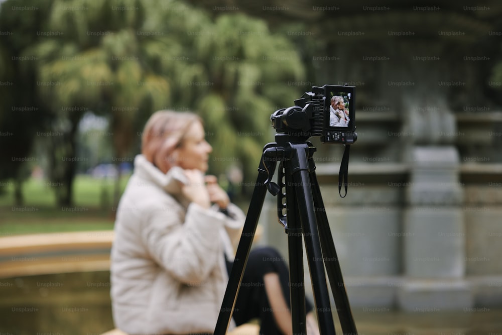 a woman sitting on a bench with a camera on a tripod