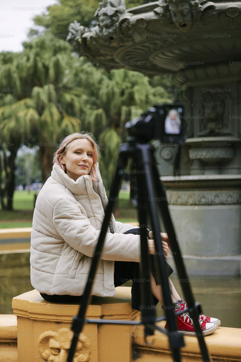 a woman is sitting on a bench with a camera