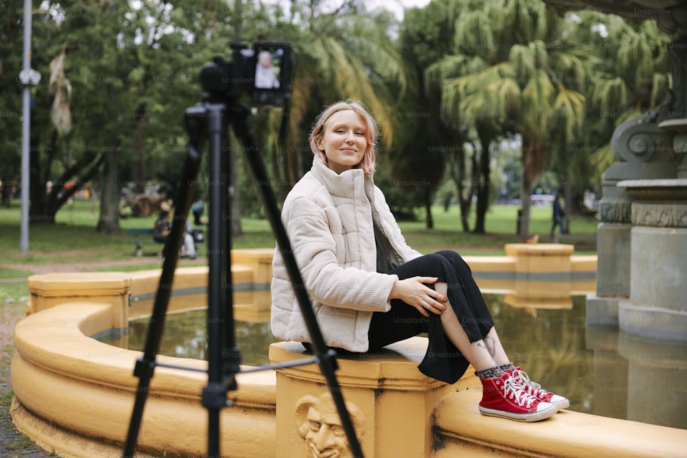a woman sitting on a fountain with a camera next to her