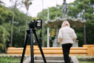 Una mujer de pie junto a una cámara encima de un trípode