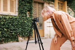 a woman leaning over a camera on a tripod
