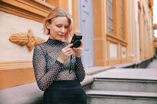 a woman in a polka dot shirt looking at her cell phone